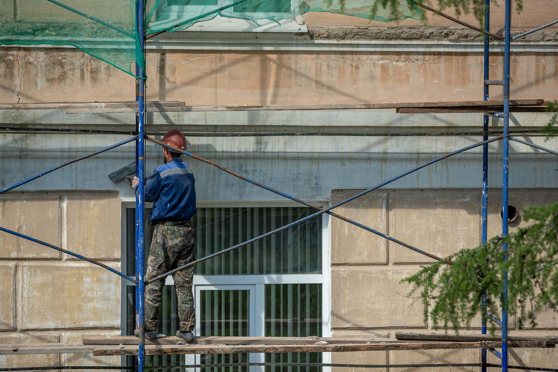 Handwerker auf einem Gerüst arbeitet an einer Hausfassade